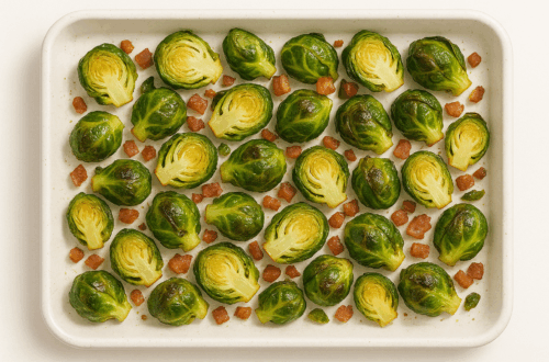 Roasted Brussels sprouts with crispy pancetta on a white baking tray.