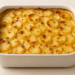 Golden scalloped potatoes baked with Gruyère cheese in a white dish on a neutral background.